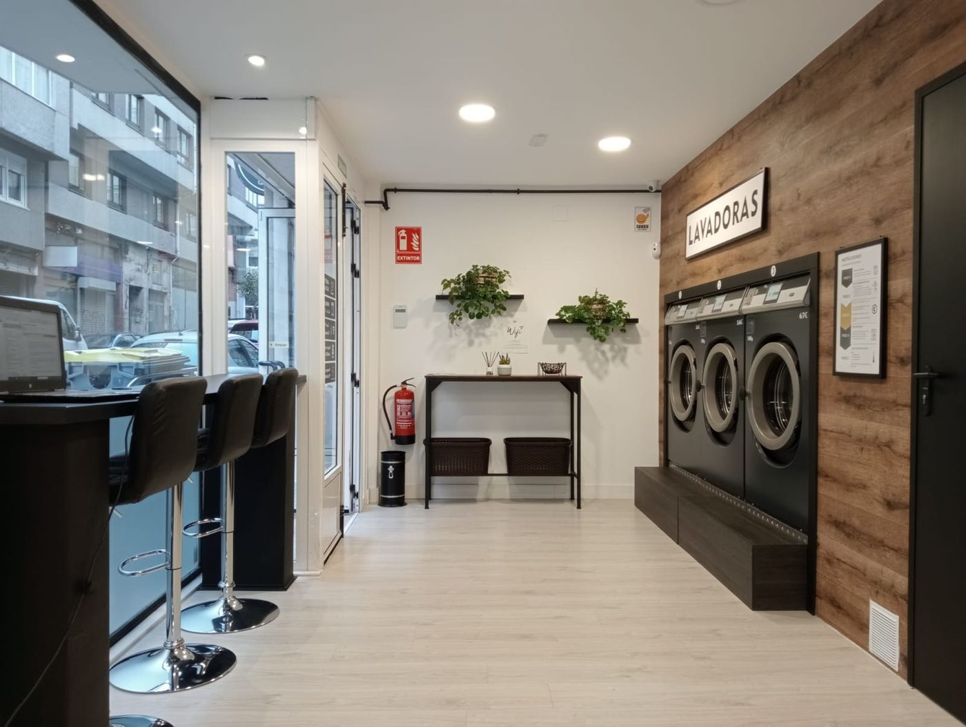 Fila de tres lavadoras Lavavut sobre pared de madera, con cestos y plantas al lado
