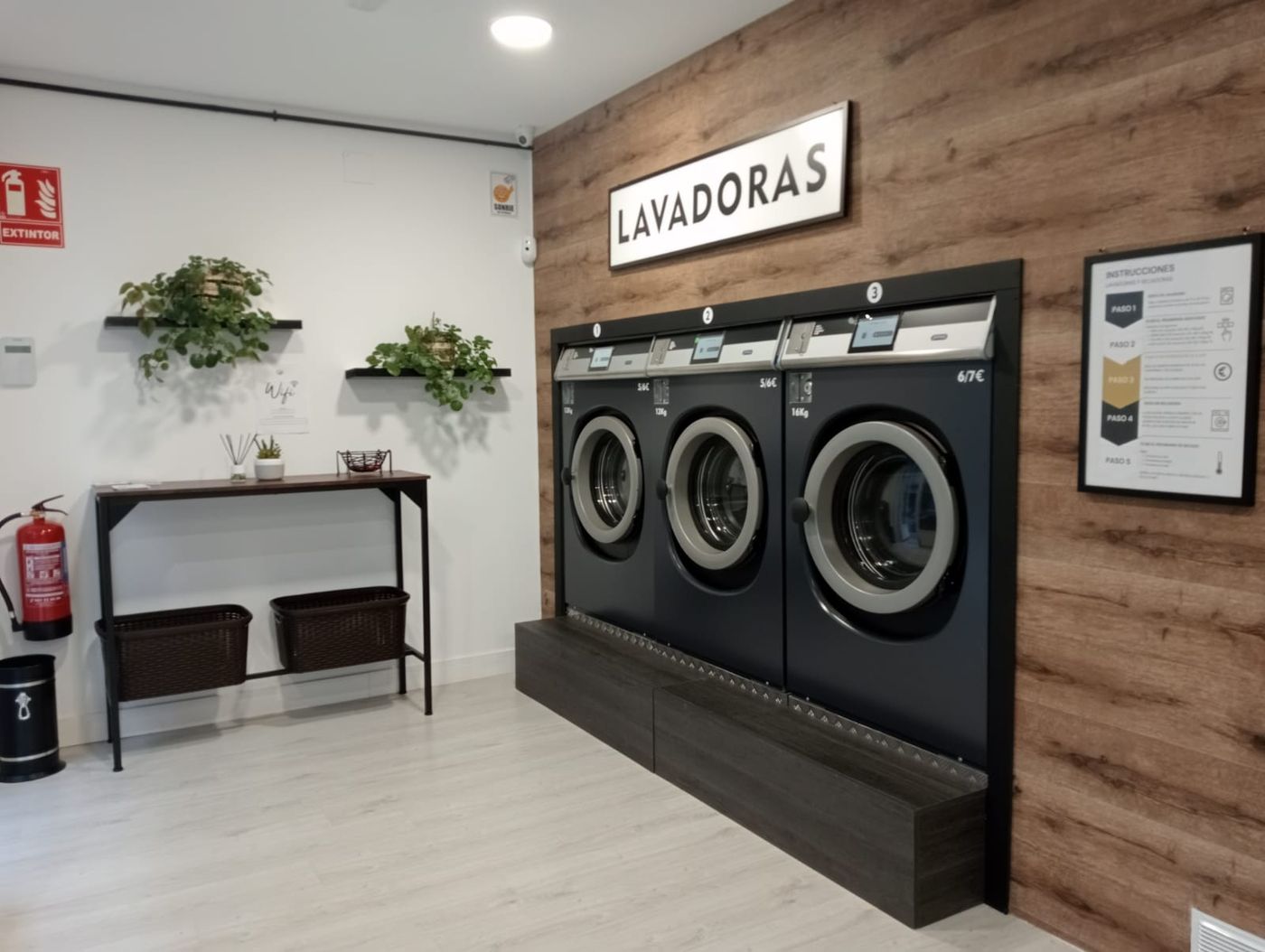 Sala de Lavavut con secadoras industriales, zona de doblado y sofá