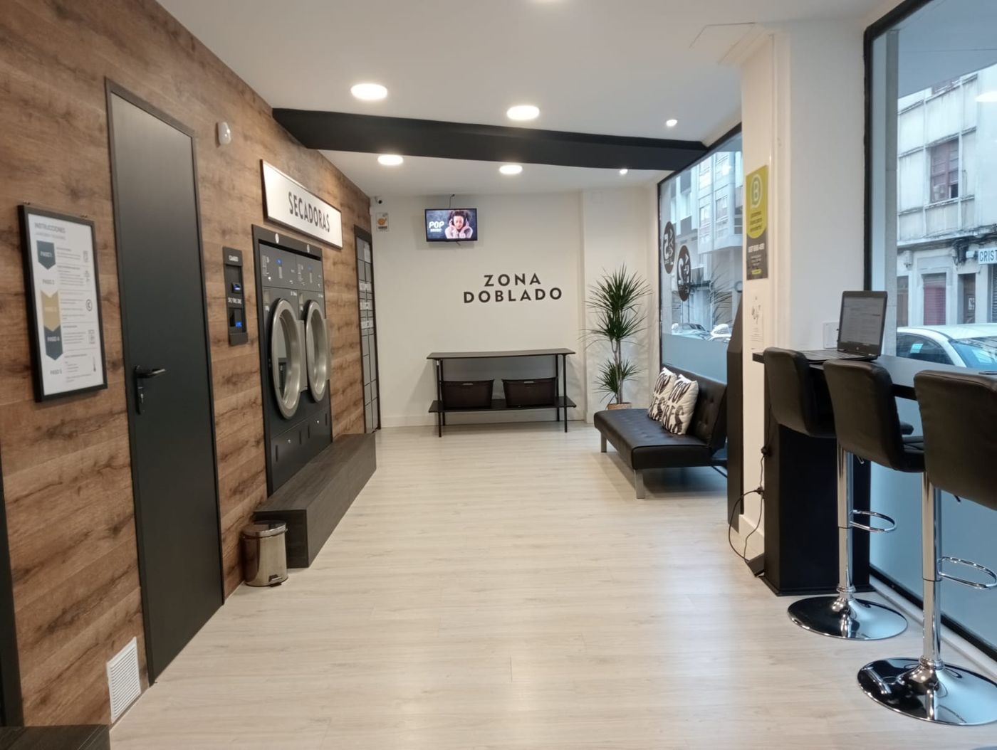 Zona de doblado con mesa y cestas, secadoras a un lado y taquillas de Amazon Hub