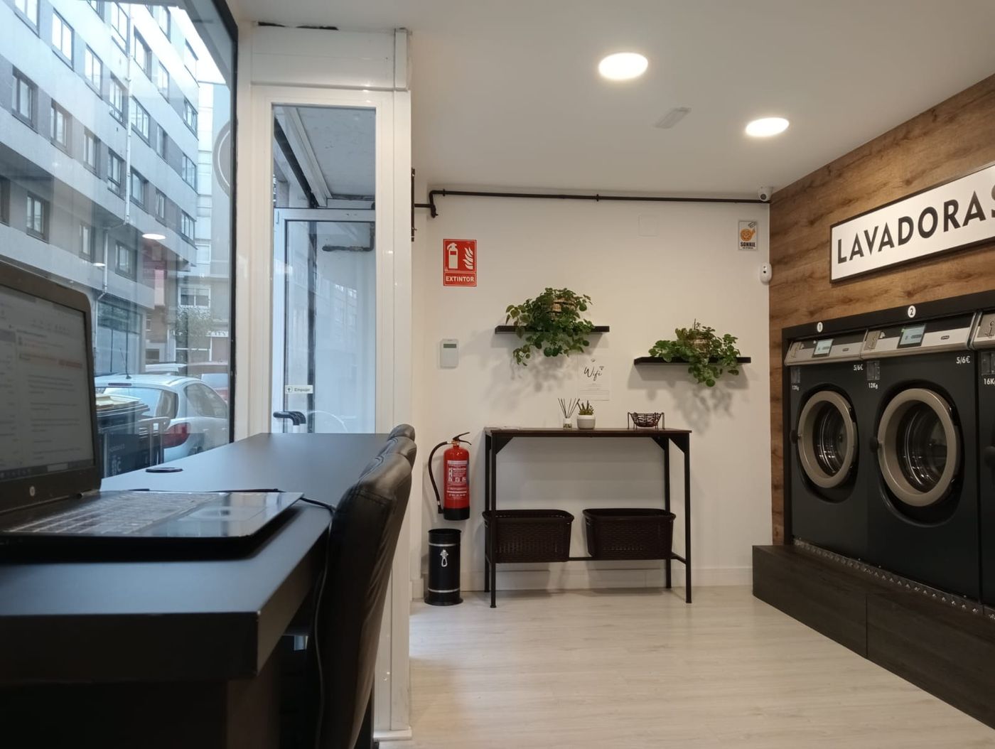 Barra alta con taburetes junto al escaparate y un portátil abierto